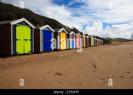 Row of brightly colored beach huts on sand beach blue sky with white clouds Stock Photo