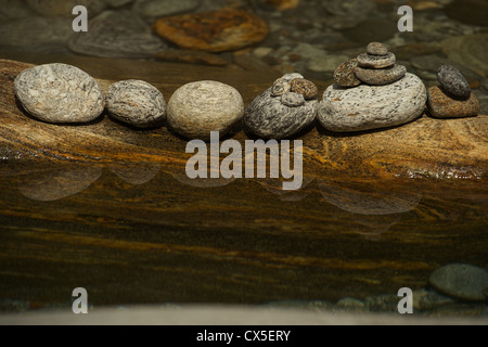 Stones in a row on a mother rock in water reflected in water. River Verzasca in Ticino. Stock Photo