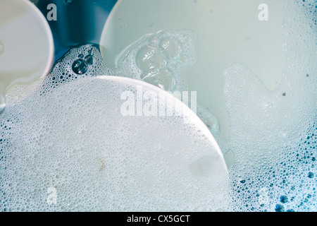 Dirty plates and dishes in a washing up bowl full of soapy water Stock Photo