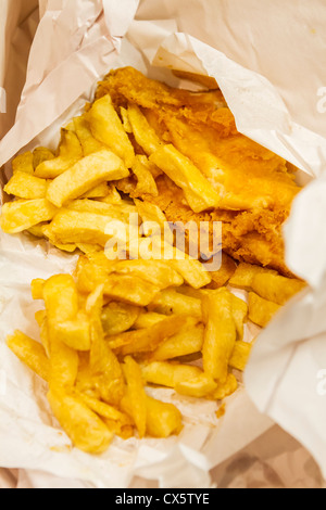 traditionally fried fish and chips wrapped in paper ready to be served Stock Photo