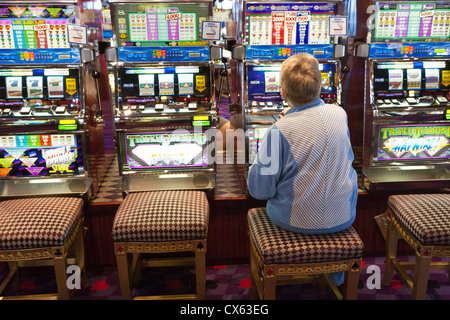 Senior woman playing slot machines in casino on cruise ship-Pacific Ocean off Long Beach, California, USA. Stock Photo
