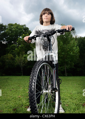 Artistic dramatic portrait of a ten year old boy standing with a bicycle in the nature Stock Photo