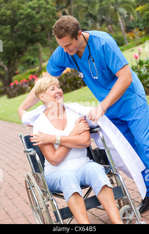 caring doctor or nurse giving his jacket to a senior patient Stock Photo