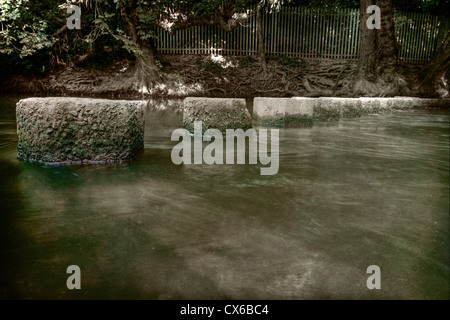 Stepping stones across River Mole in Surrey provide a safe passage through the deep water underwater stones pebbles on river bed Stock Photo