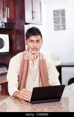 young Indian man in traditional clothing using laptop at home Stock Photo