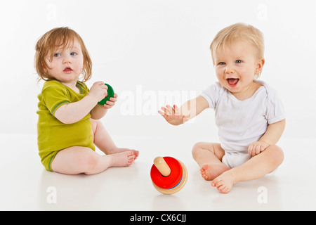two babies girls playing together with color toys Stock Photo - Alamy