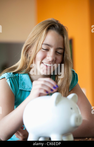 Girl putting coin in piggy bank Stock Photo - Alamy