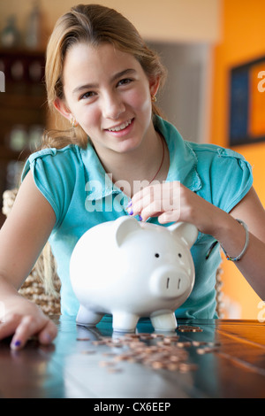 Girl puts coin in piggy bank Stock Photo