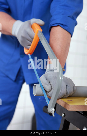 Plumber sawing grey plastic pipe Stock Photo