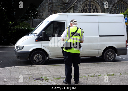 Traffic warden (civil enforcement officer parking) at work on white van man. Stock Photo