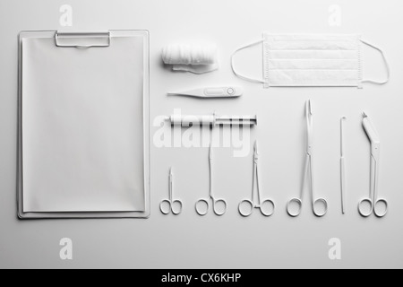 Clipboard, various medical scissors and instruments painted white and arranged neatly Stock Photo