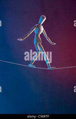 An artist's figure walking a tightrope Stock Photo
