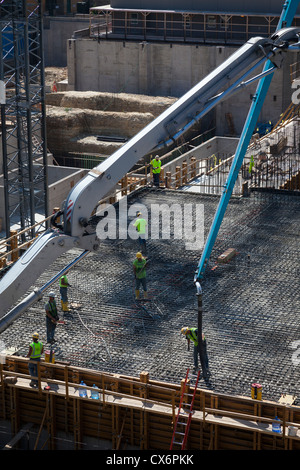 Construction workers pouring cement at construction site. Stock Photo