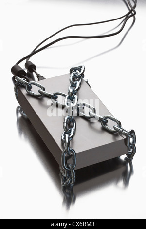 A thick metal chain wrapped around an external hard drive Stock Photo