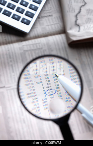 A magnifying glass magnifying a circled figure on a financial page Stock Photo