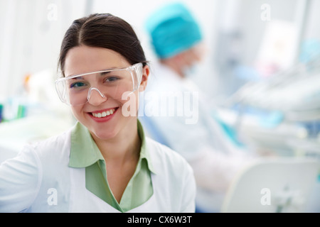 Pretty assistant in protective eyewear looking at camera Stock Photo