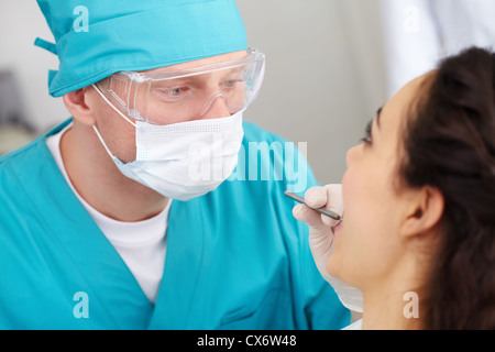 Male dentist in protective uniform carrying out mouth checkup Stock Photo