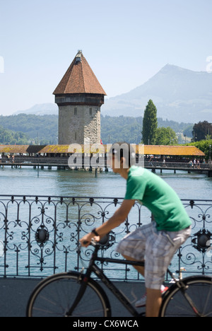 A bicyclist rides through Lucerne, Switzerland. The Water Tower and Chapel Bridge are in the background. Stock Photo