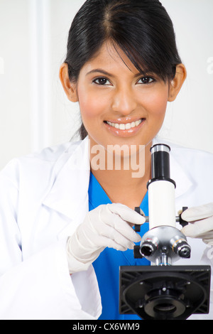 young female hispanic lab technician using microscope Stock Photo