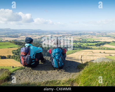 Male and female hikers ovelooking Great Ayton village from top of Roseberry Topping near Great Ayton, North Yorkshire Stock Photo