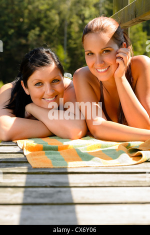 Mother and daughter sunbathing on pier smiling teen relaxing vacation