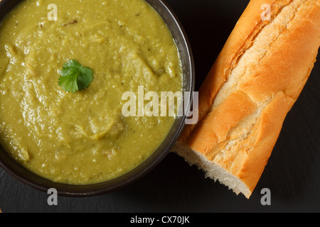 Bowl of homemade pea and ham soup in with crusty french bread Stock Photo