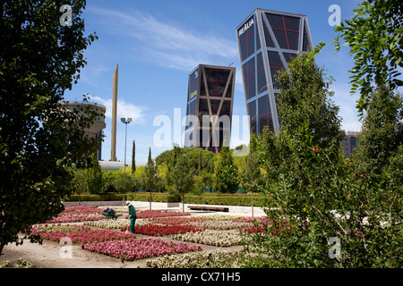 A gardener tends to flowers in the Parque Cuarto Deposito, Canal de Isabell II in front of the two leaning towers,Torres Kio, Stock Photo