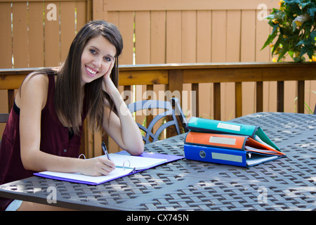 A pretty girl doing homework on a patio outside. Stock Photo