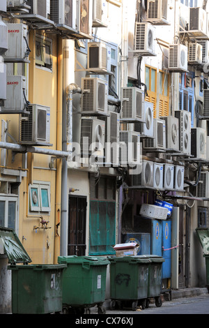 Air conditioning units clustered on the side of buildings down alleyway. Stock Photo