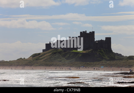 Bamburgh Castle, Northumberland, with waves and people enjoying a Summers day on the beach. Stock Photo