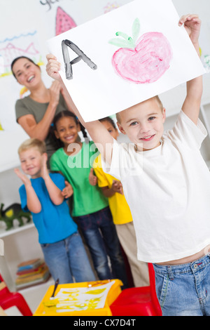 proud kindergarten boy holding painting high Stock Photo