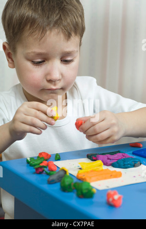 A young boy playing with various colored child's play clay Stock Photo