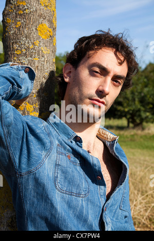 Man leaning against tree in park Stock Photo