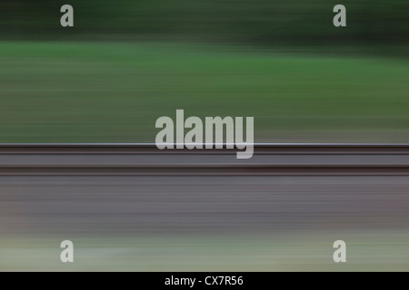 Railroad tracks and grass seen in blurred abstract pattern from moving train Stock Photo