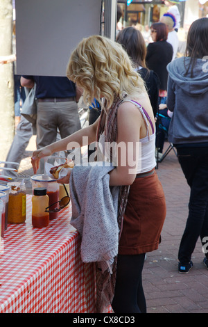 Young woman putting tomato ketchup on a hot dog at Carlisle Jubilee celebrations in the city centre of Carlisle Cumbria, England Stock Photo