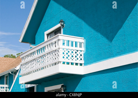 Bright blue colored Abandon condominium with white lattice balcony due to recession Stock Photo