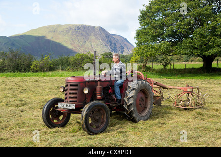 BUTTERMERE, ENGLAND - SEPTEMBER 5: Farmer threshing corn using antique tractor on September 5, 2012.