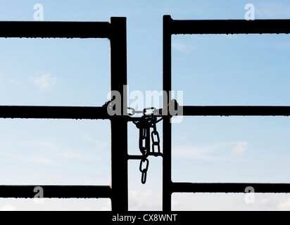 Chained metal farm gate silhouette in the english countryside Stock Photo