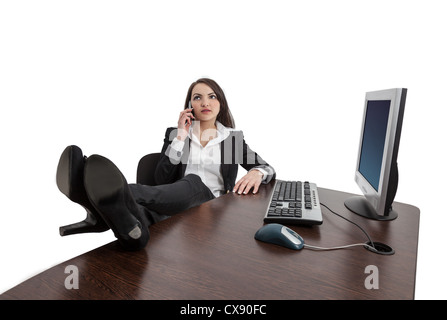 Relaxed businesswoman with her legs on the desk using a mobile phone, against a white background. Stock Photo