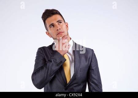 Young businessman thinking and looking up (isolated on gray Stock Photo