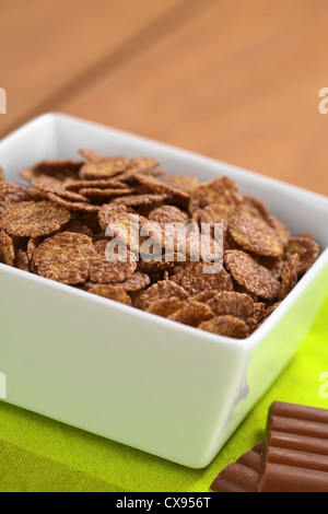 Bowl of chocolate corn flakes cereal with chocolate bars on the side (Selective Focus, Focus in the middle of the cereal) Stock Photo
