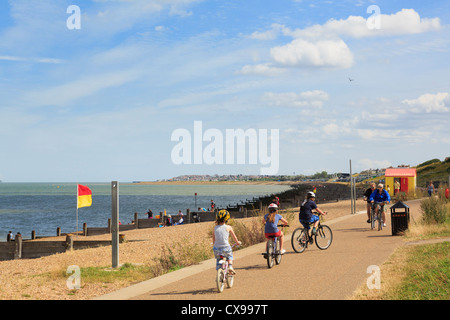 People cycling on Whitstable seafront promenade along Saxon Shore Way in Tankerton Bay to Swalecliffe on north Kent coast. Whitstable Kent England UK Stock Photo