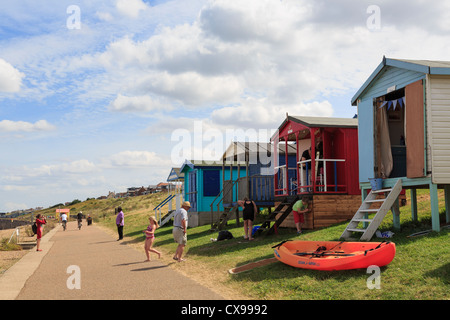 People on Whitstable seafront promenade with beach huts on north Kent coast Thames estuary at Tankerton, Whitstable, Kent, England, UK Stock Photo