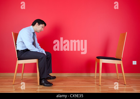 Businessman sited next to a red wall Stock Photo