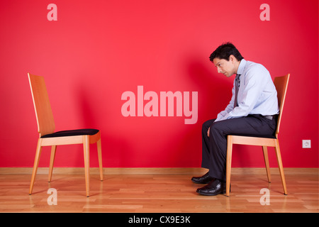Businessman sited next to a red wall Stock Photo