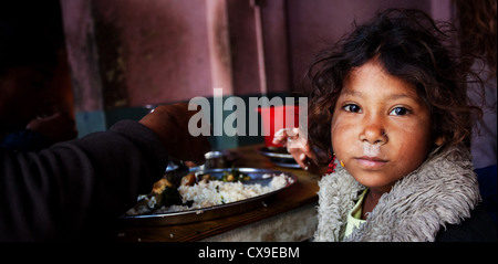 Poor girl and her family eating in a dirty cafe in Kathmandu, Nepal Stock Photo