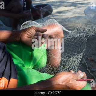 Men mending their fishing nets on a beach, Dili, East Timor Stock Photo