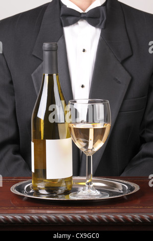 Waiter wearing a tuxedo with a White Wine Bottle With Blank Label and Glass on Silver Tray Stock Photo