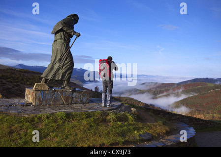 A pilgrim stands next to the monument at Alto San Roque near O'Cebreiro in Spain. Stock Photo