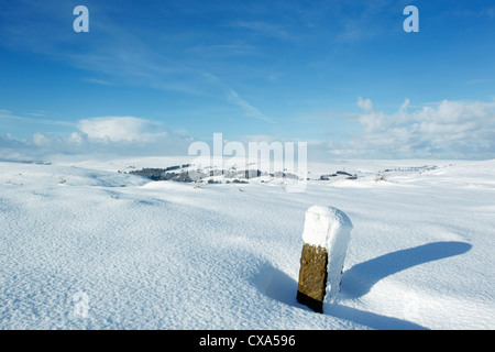 Winter view of snow covered moors, looking west from Castleton Rigg with a parish boundary stone in the foreground Stock Photo